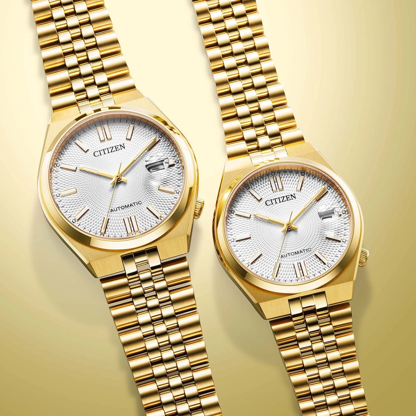 Zwei goldene Citizen Automatikuhren auf goldenem Hintergrund.