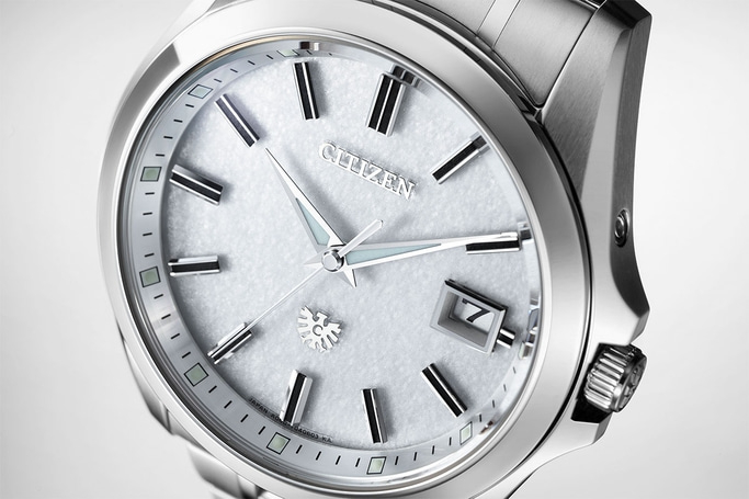 Nahaufnahme einer silbernen Citizen-Uhr mit strukturiertem weißem Zifferblatt und Datumsanzeige.