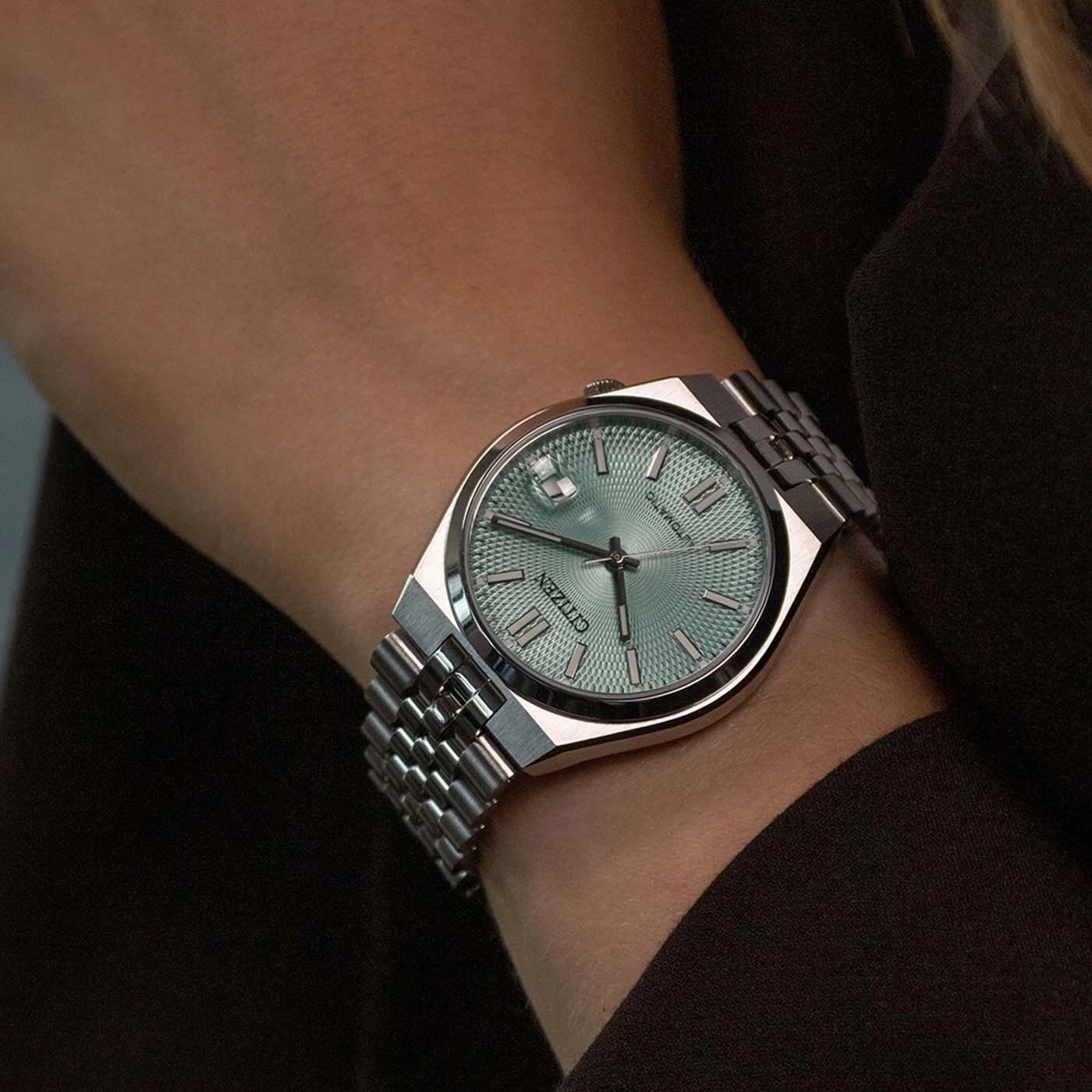Silberne Citizen-Uhr mit hellblauem Zifferblatt an einem Handgelenk.