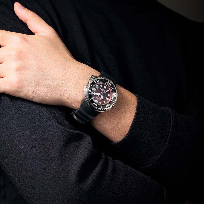 Mann trägt Citizen-Uhr mit schwarzem Armband und rotem Zifferblatt.