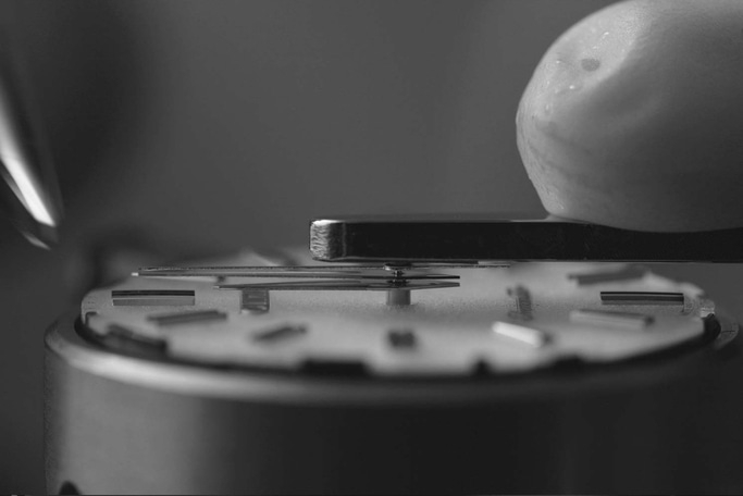 Nahaufnahme des Uhrenmechanismus, der mit Werkzeugen und Präzision zusammengebaut wird.