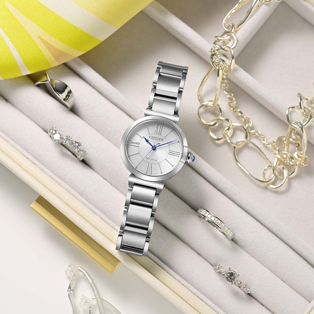 Une montre Citizen Eco-Drive argentée avec des bagues et des bracelets dans une boîte à bijoux.